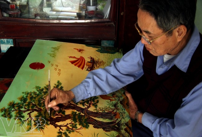 Nghệ nhân Đinh Khắc Tuyến (làng Cát Đằng) đang chỉnh sửa một bức tranh sơn mài. 