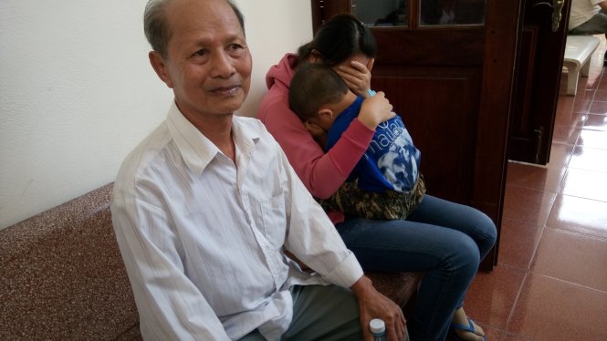 Cha ông Minh buồn rầu còn vợ, con ông Minh ôm nhau khóc tại sân tòa - Ảnh: Đức Tuyên 