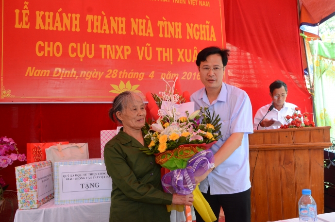 Ông Đinh Xuân Hùng, Phó giám đốc Sở GTVT Nam Định tặng quà và hoa cho cựu TNXP Vũ Thị Xuân 