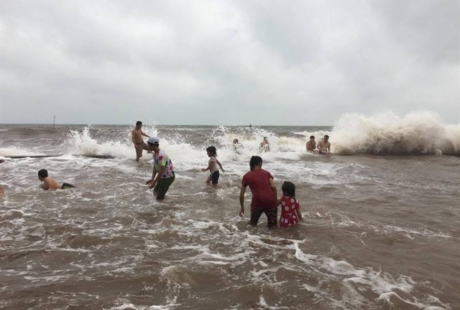 Nước biển ở Quất Lâm dâng cao nhưng người dân vẫn ra tắm.
