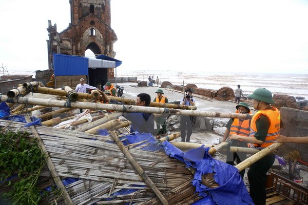 Cán bộ đồn Biên phòng Văn Lý giúp người dân khắc phục sau bão số 1 đi qua tại khu vực bãi biển xã Hải Lý (Hải Hậu). (Ảnh: Minh Quyết/TTXVN) 