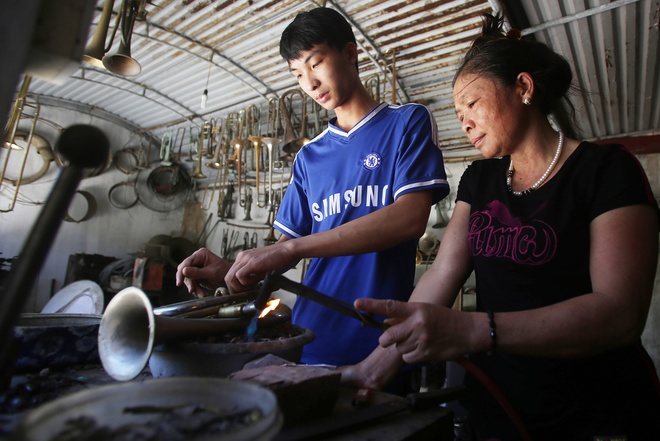 Nguyễn Trung Kiên 19 tuổi (trái), tiếp xúc với nghề từ năm 10 tuổi. Cậu cho biết: “ Trong gia đình, các thành viên đều có thể làm hoàn thiện một chiếc kèn, ai cũng được học nghề từ nhỏ nên làm thành thạo”.