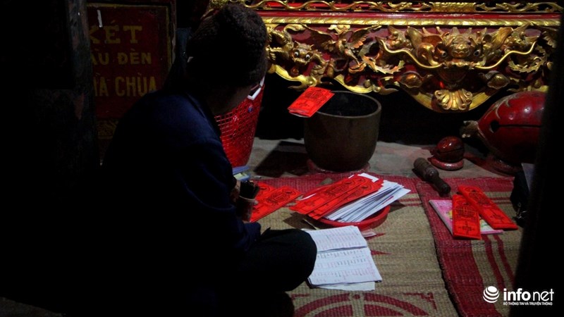 Một thầy chùa đang ngồi xếp lại những "lá sớ" (ghi tên tuổi, mong ước của người đến xin).