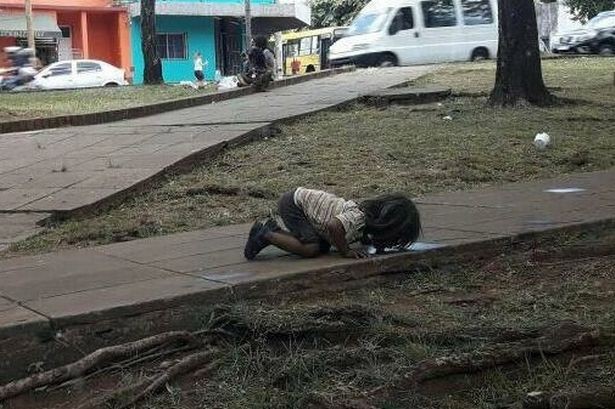 Bức ảnh em bé nghèo quỳ gối, uống vũng nước trên đường khiến cả thế giới rúng động